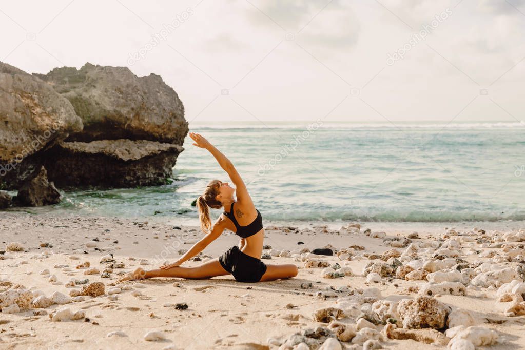 Young woman practice yoga at beach with sunset or sunrise.