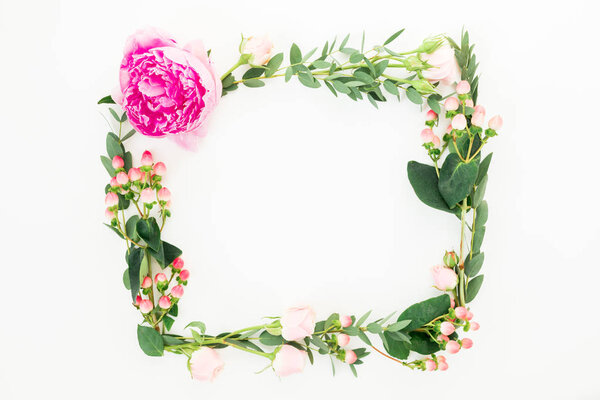 Floral frame with pink flowers, hypericum and eucalyptus branches on white background. Flat lay, top view