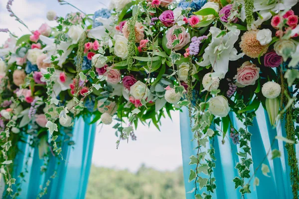 Floral decoration with blue cloth for wedding ceremony. Wedding arch with beautiful flowers.