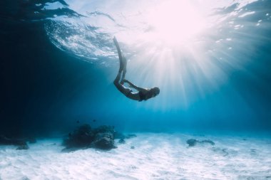 Kadın freediver dalış yüzgeçleri ile kumlu deniz üzerinde. Serbest dalış mavi okyanus