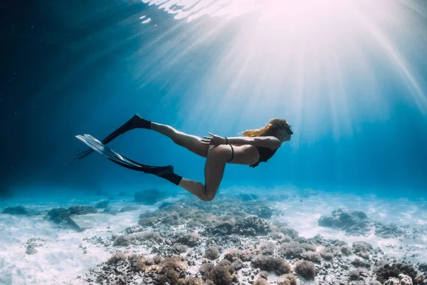 砂浜の海と太陽光線水中でフィン スイミングのきれいな女性フリーダイバー — ストック写真