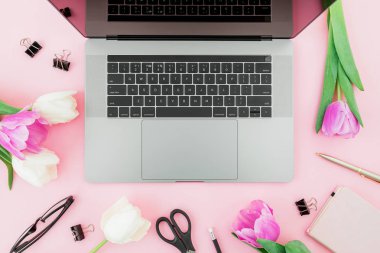 Yeni laptop, süt, Lale çiçek, gözlük, kalem ve pembe bir arka plan için makaslar. Düz yatıyordu. Üstten Görünüm.