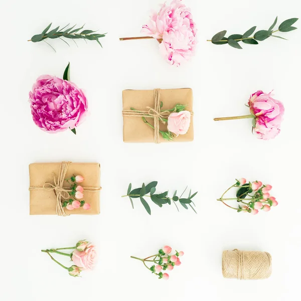 Floral composition of peonies, roses, hypericum and eucalyptus with clipboard and gifts box on white background. Flat lay