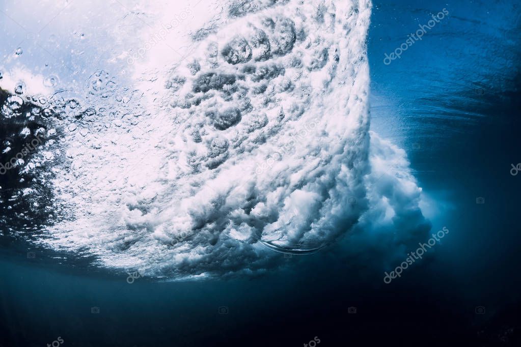 Wave underwater with air bubbles and sun light. Ocean in underwater