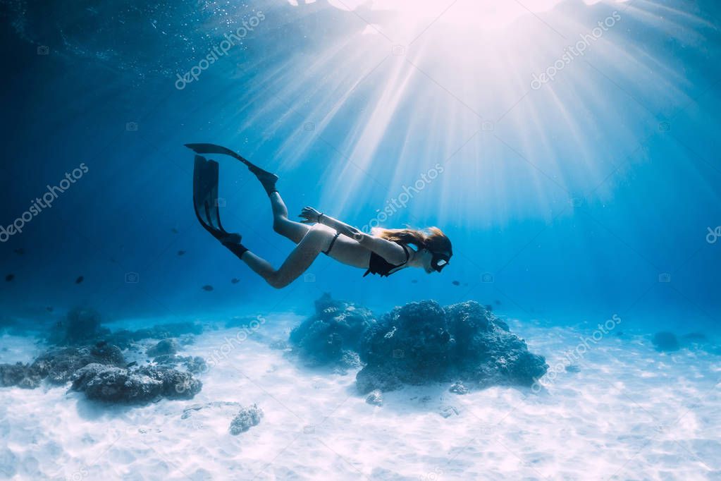 Free diver glides over sandy sea with fins. Freediving in blue ocean