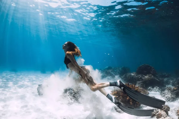 フィン付き女性フリーダイバー砂底と太陽光線水中海を泳ぐ — ストック写真