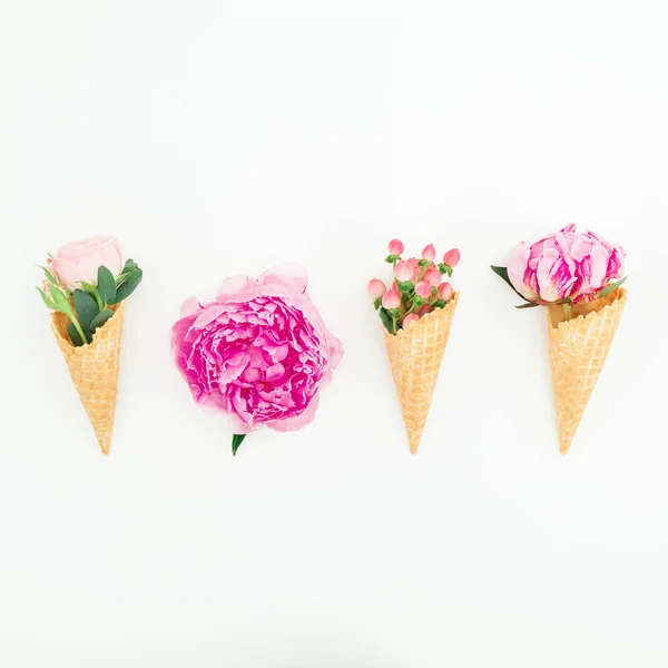 Floral concept with peonies flowers, roses petals and waffle cones on white background. Flat lay, top view