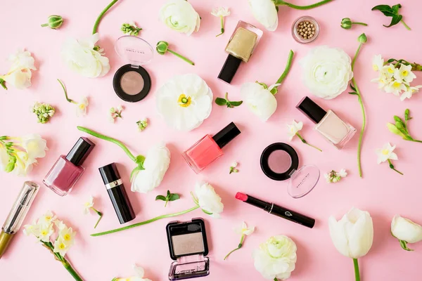 Beauty female blogger composition with flowers, cosmetics and accessory on pink background. Top view. Flat lay.