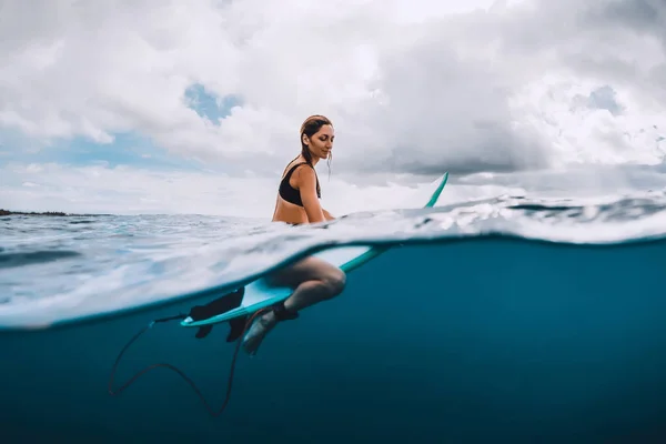 若く魅力的なサーフィン青い海でサーフボードに女の子座って — ストック写真