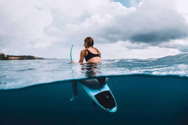 若く魅力的なサーフィン青い海でサーフボードに女の子座って — ストック写真