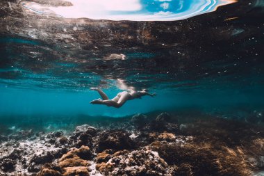 Genç kadın sualtı tropikal mavi okyanusta yüzmeye