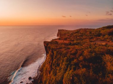 Kayalık uçurum ve okyanus sıcak günbatımı hava görünümünü Bali