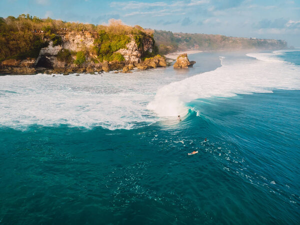 Aerial view with surfers and barrel blue wave in ocean, Padang Padang
