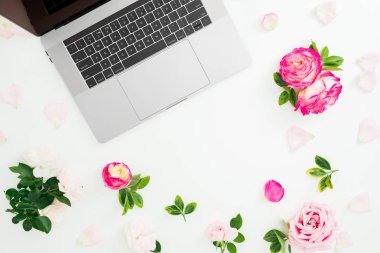 Beyaz arka planda laptop, güller çiçekler ve yaprakları. Düz yatıyordu. Üst görünüm.