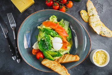 Yumurta, somon balığı, avokado, domates ve gri arka planda ızgara tost ile salata. Düz yatma