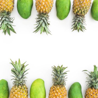 Beyaz arka planda ananas ve mango meyveleri çerçevesi. Düz yatıyordu, üst görünüm