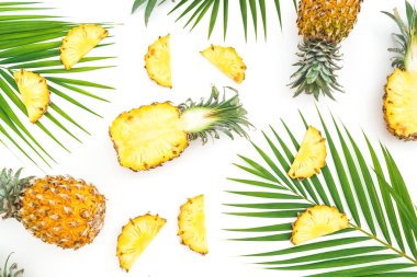 Dilimlenmiş ananas meyve ve palmiye beyaz arka planda yaprakları ile desen. Düz yatıyordu, üst görünüm.