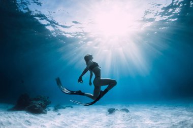 Kumlu deniz üzerinde yüzgeçli kadın serbest dalgıç. Mavi okyanusta serbest dalış