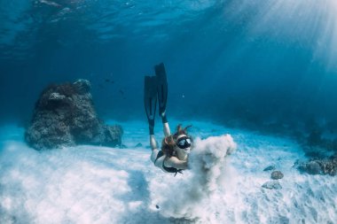 Kanatlarla kumlu deniz üzerinde beyaz kum ile Freediver kız. Okyanusta sualtı serbest dalış