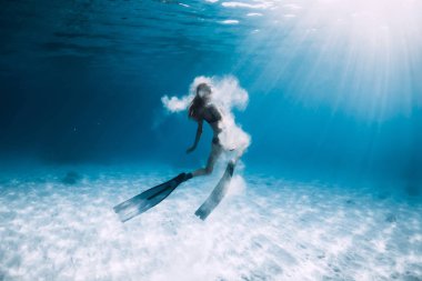 Yüzgeçli kadın serbest dalgıç ve kumlu deniz üzerinde beyaz kum. Mavi okyanusta sualtı serbest dalış