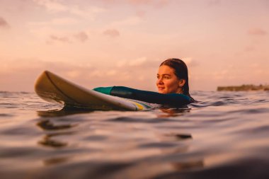 Okyanusta yüzen bir sörf tahtası üzerinde mükemmel bir vücut ile Surfgirl. Gün batımında sörf