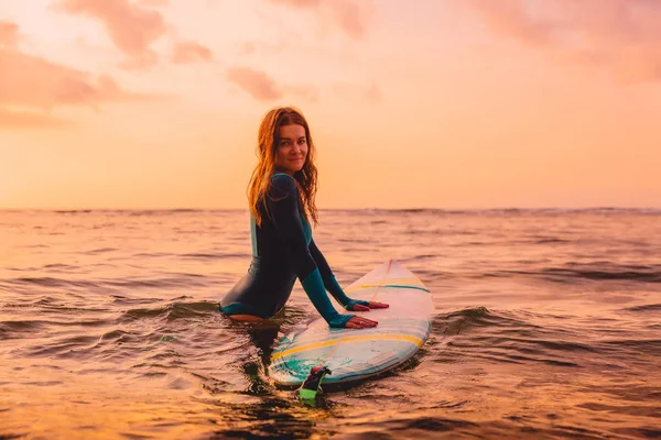 海のサーフボードでポーズ魅力的なサーファーの女の子 夕暮しのサーフィン — ストック写真