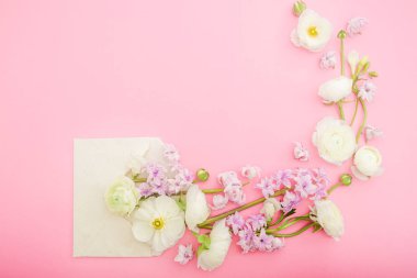 Çiçek çerçeve pembe arka plan üzerinde zarf ile çiçekyapılmış. Düz döşeme, üst görünüm.