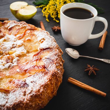 Masada kahve bardağı, elma meyve, tarçın ve mimoza çiçekleri ile lezzetli elma kek.