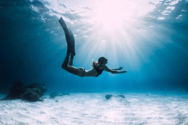 Kumlu deniz üzerinde yüzgeçli bir kadın. Okyanusta serbest dalış