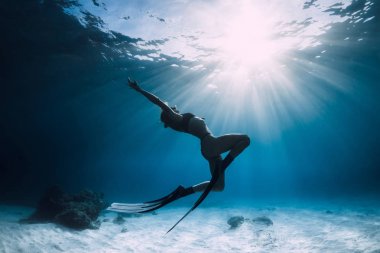 Woman freediver over sandy sea with fins. Freediving in ocean clipart