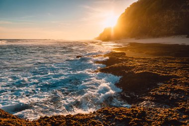 Gün batımında okyanus, dalgalar ve güneş ışığı ile tropikal plaj