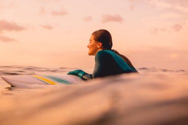 Okyanusta sörf tahtası üzerinde mükemmel bir vücut ile çekici sörf kız. Gün batımında sörf