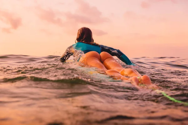 海に浮かぶサーフボードの美しいサーフガール 夕暮しのサーフィン — ストック写真