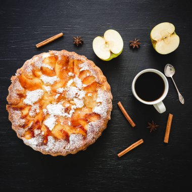 Siyah arka planda elma pastası, elma ve kahve bardağı. Düz yatıyordu, üstteki görünüm.