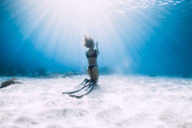 Kumlu denizin üzerinde yüzgeçleriyle poz veren özgür bir kadın. Hawaii 'de serbest dalış