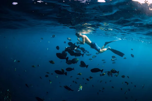 フリーダイバーの男は海で魚の泳ぎと給餌学校 — ストック写真