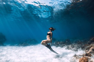 Yüzgeçlerle kumlu denizüzerinde poz veren kadın serbest dalgıç. Hawaii'de serbest dalış