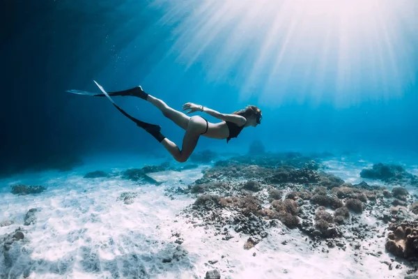 Free diver glides over sandy sea with fins. Freediving in blue sea