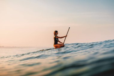 12 Nisan 2019. Bali, Endonezya. Okyanusta Paddle sörf kız Stand Up. Bali'de Paddle sörf stand up