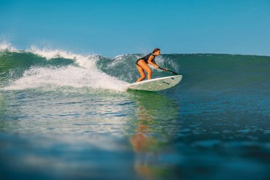12 Nisan 2019. Bali, Endonezya. Okyanus dalga üzerinde Paddle sörf kız binmek Stand Up. Bali'de Paddle sörf stand up