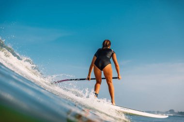 12 Nisan 2019. Bali, Endonezya. Okyanus dalga üzerinde Paddle sörf kız binmek Stand Up. Bali'de Paddle sörf stand up