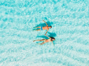 Kocası olan hamile kadın mavi denizde yüzer. Havadan görünüm