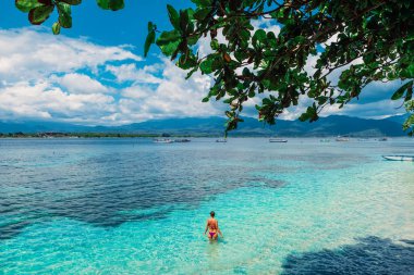 Genç bikini kadın tropikal adada mavi okyanusta dinlenmek