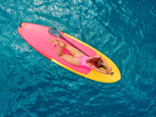 Femme se détendre sur stand up paddle board sur une mer bleue calme — Photo