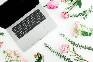 Beyaz arka planda laptop ve pembe çiçekler. Üst görünüm. Düz yatma.