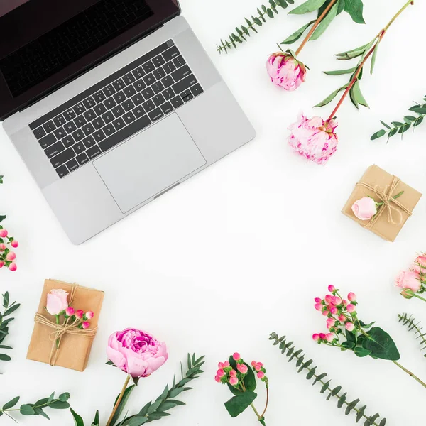 Floral frame with laptop, gifts and pink flowers on white backgr