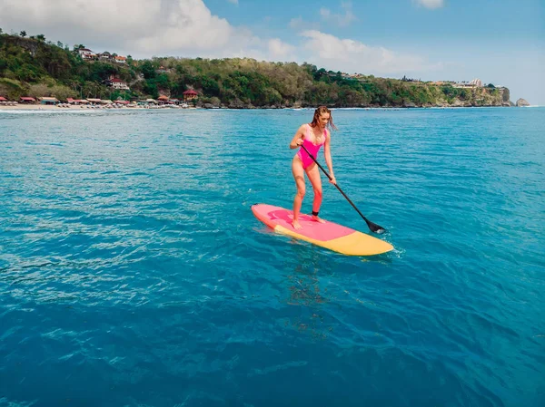 Femme debout planche à pagaie en mer bleue. Plan aérien — Photo