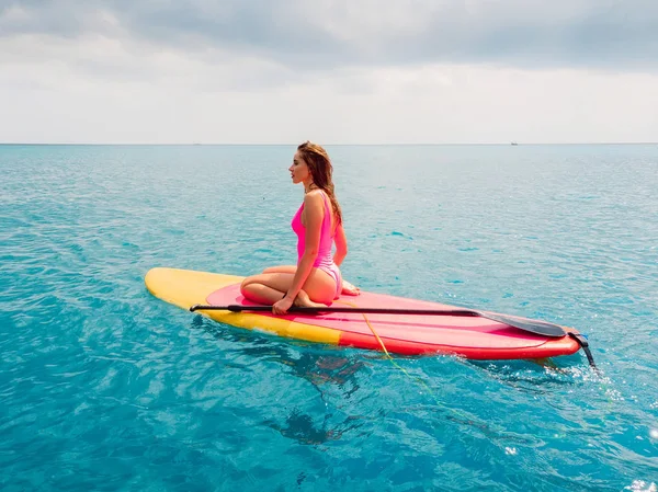 Mujer relajarse en stand up paddle board en un océano azul tranquilo — Foto de Stock