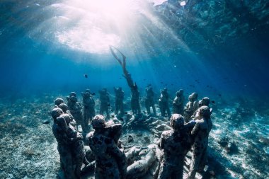 Yüzgeçli kadın serbest dalgıç sualtı heykellerinin yakınına daldı. Okyanusta sualtı turizmi.