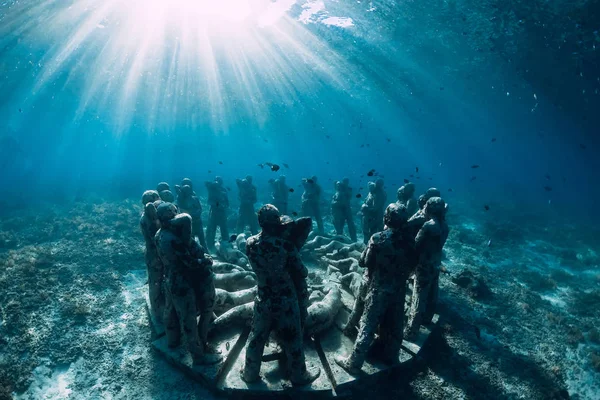 Underwater statues in blue ocean with fish. Underwater tourism in ocean.